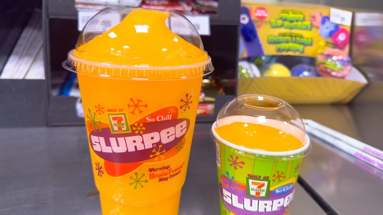 An orange and mango Slurpee in a plastic cup