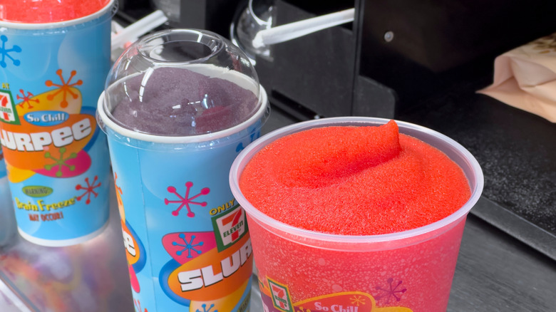 Cups full of Slurpee in cherry and grape flavors