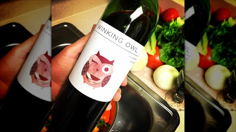 hand holding a bottle of Winking Owl shiraz