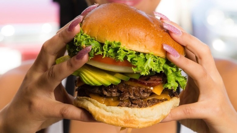 hands holding burger with vegetables and cheese from Burger Boss