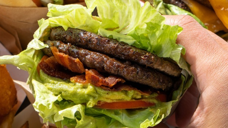 hands holding paleo burger from Elevation Burger