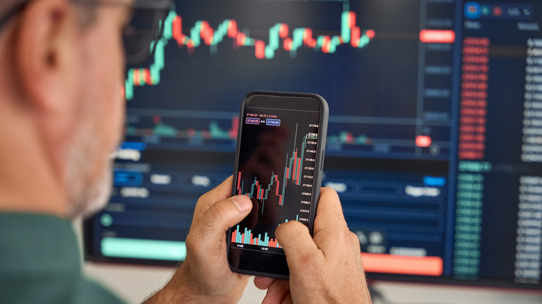 Person watches share prices on a computer and phone