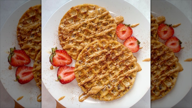 French toast waffles on a plate with strawberries and peanut butter