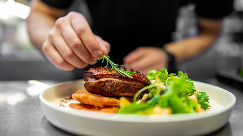 Chef garnishing steak