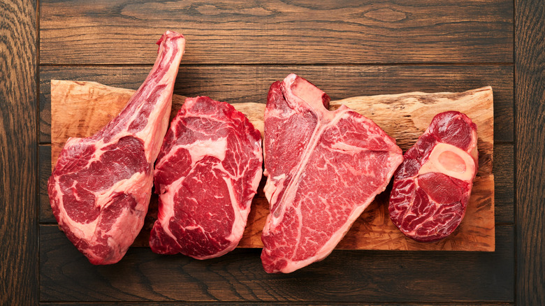 Different cuts of raw steak on a cutting board