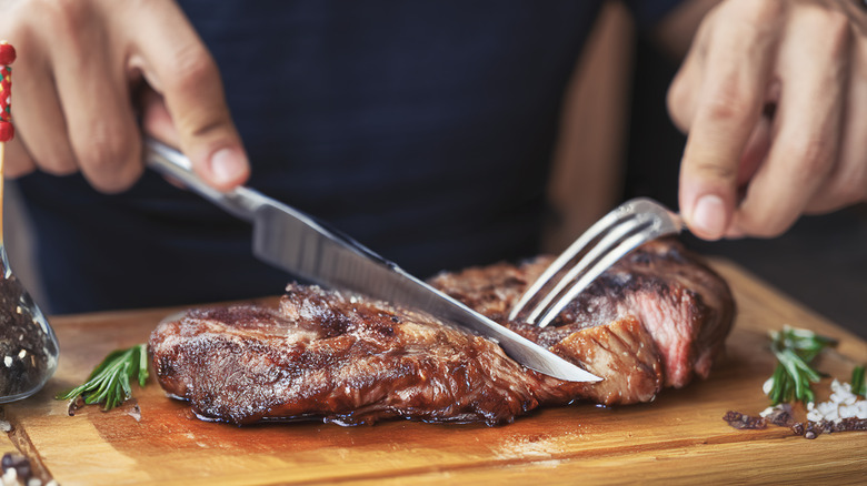 Hands cutting into steak