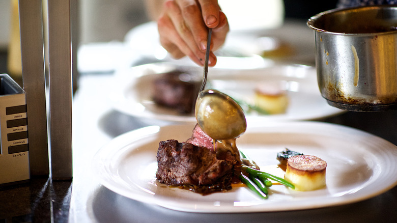 Chef plating steak in restaurant