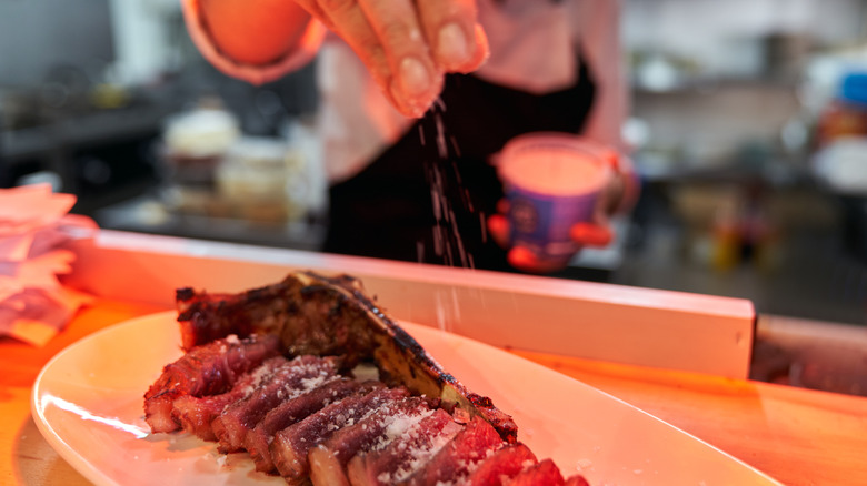 Chef putting salt on steak