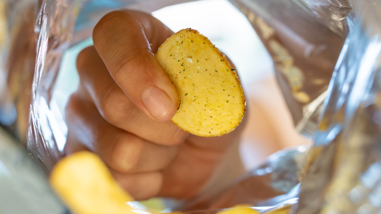 Hand grabbing chip from bag