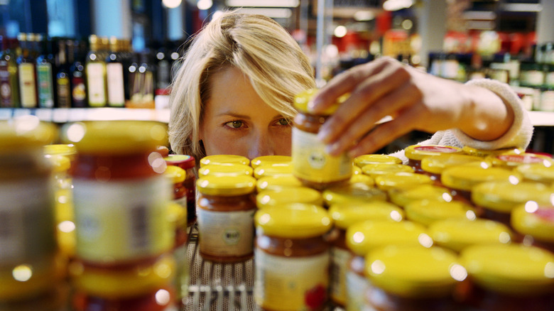 Person reading expiration date on jar in store