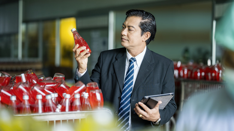 Inspector in food plant holding bottled drink