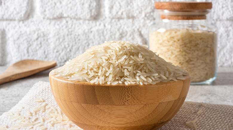 A wooden bowl full of uncooked white rice