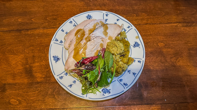 turkey, cornbread stuffing, salad, and gravy on a plate