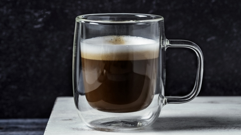 An espresso topped with milk foam in clear cup