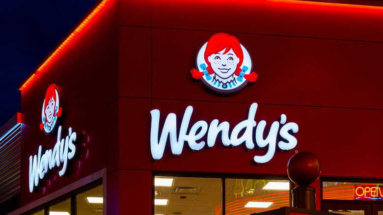 The glowing signs on the exterior of a Wendy's fast food location at night time