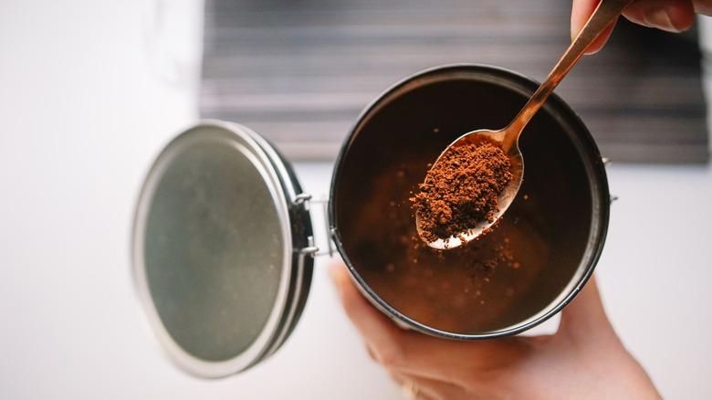 Hands spooning instant coffee out of a jar