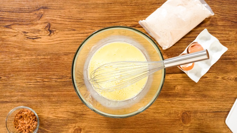 A bowl of batter with cake mix and eggs on the side