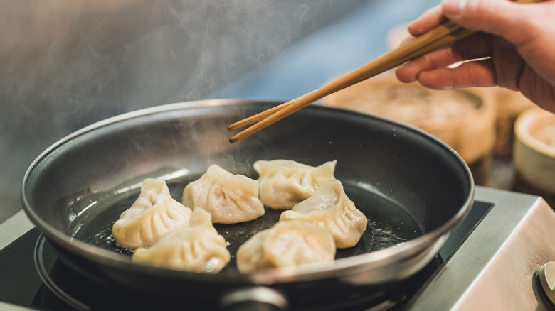 Pan searing dumplings with chopsticks