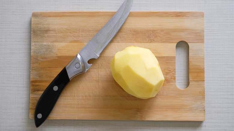 knife and potato on a cutting board