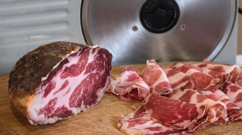 Coppa on a board by an electric slicer