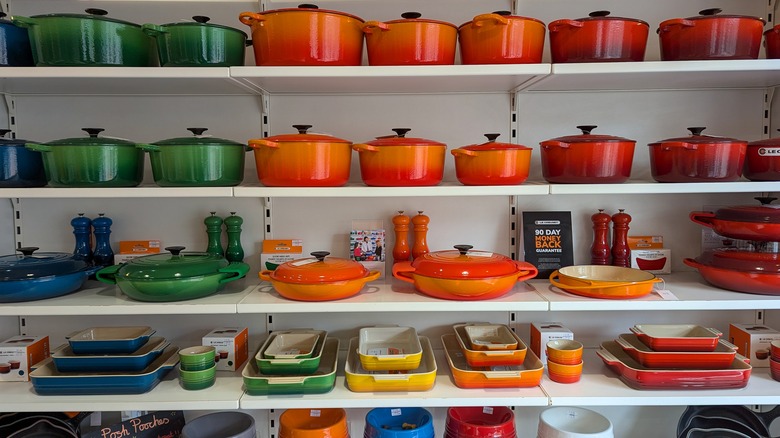 Shelves of blue, green, orange, and red Le Creuset pots and pans