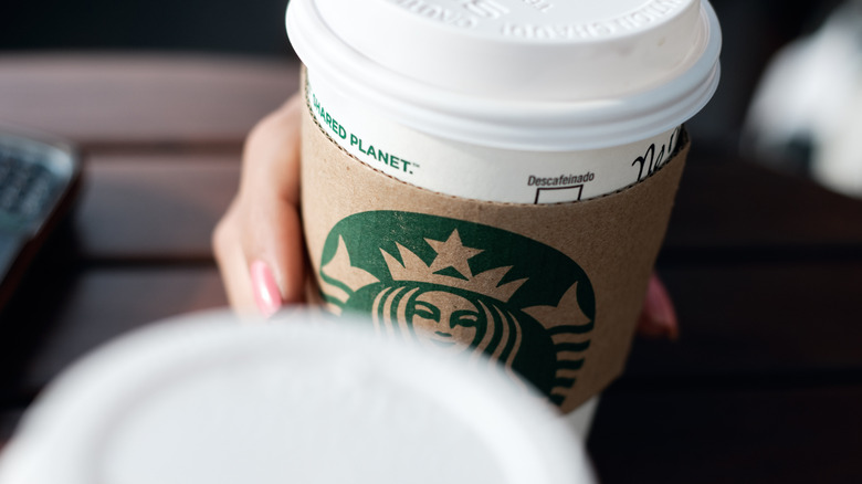 Two hands hold Starbucks coffee cups