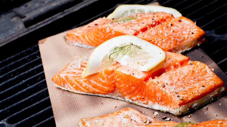 Two slices of salmon on a grill with lemon