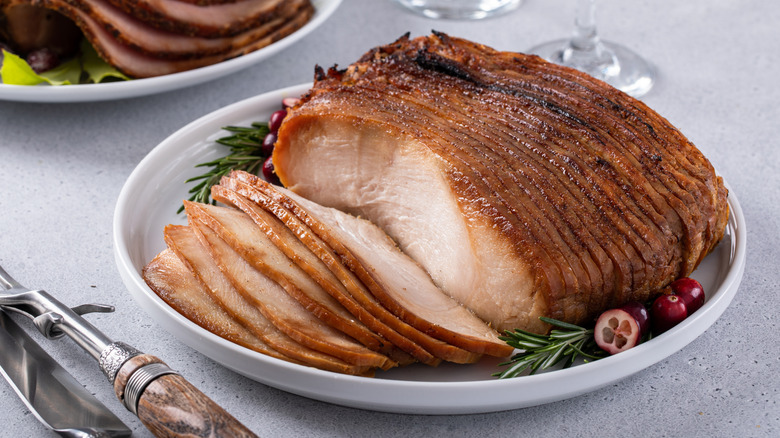 A whole turkey breast, roasted and freshly-sliced on a white plate.