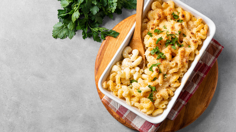 Casserole dish of mac and cheese on a wooden board