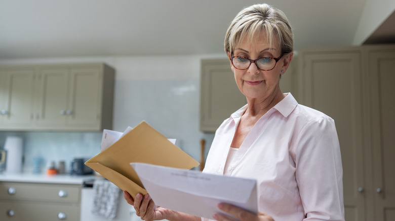 A person looks at mail in her kitchen