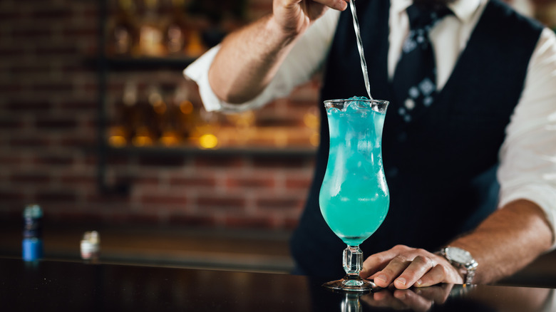 Bartender mixes a blue drink at bar