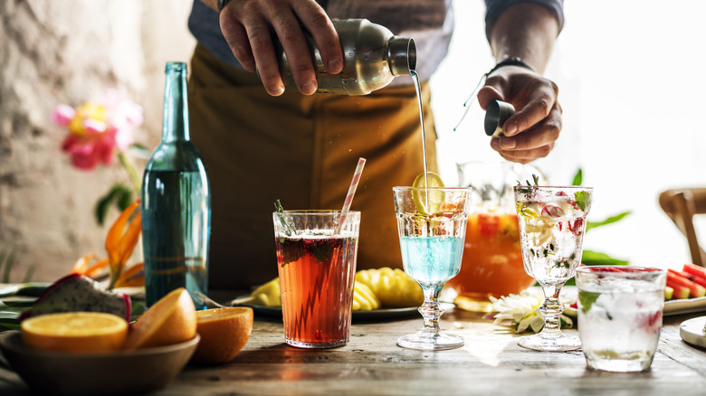 Hands preparing cocktails in sunny room