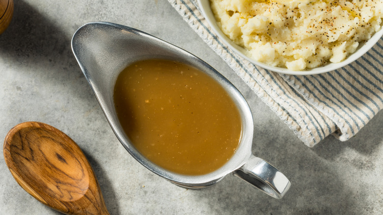 Gravy in a gravy boat next to mashed potatoes