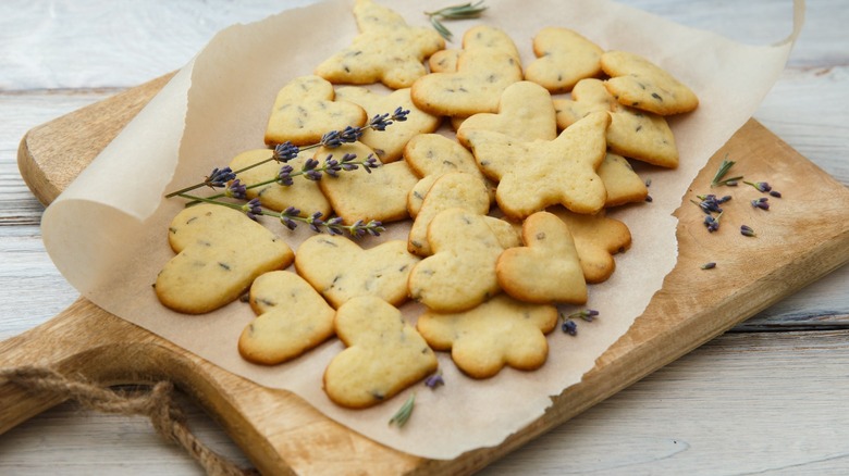 Lavender cookies on a wooden cutting board with lavender sprigs