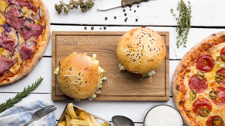 Two burgers with two pizzas on a wooden board