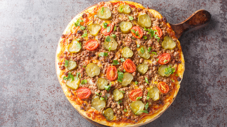 Cheeseburger-topped pizza with pickles and tomatoes