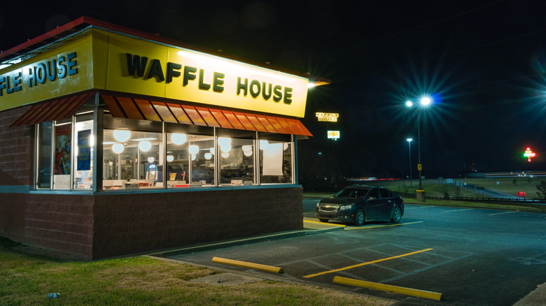 The exterior of a Waffle House and its mostly empty parking lot at night.