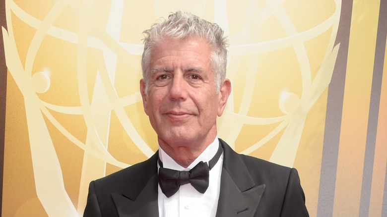 Anthony Bourdain smirking in a tuxedo on the red carpet of an an award show