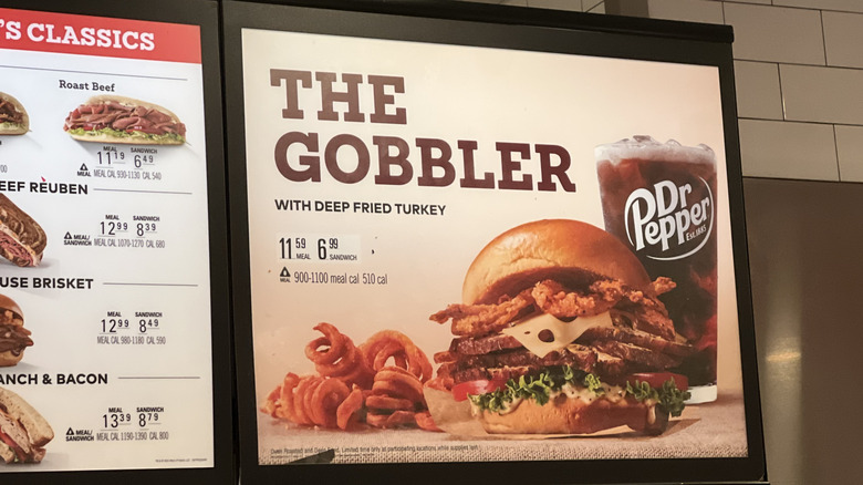 A menu sign displaying Arby's Deep Fried Turkey Gobbler sandwich