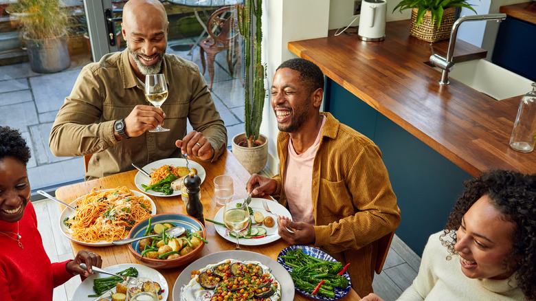 Two Black couples enjoy a meal at a table laden with food