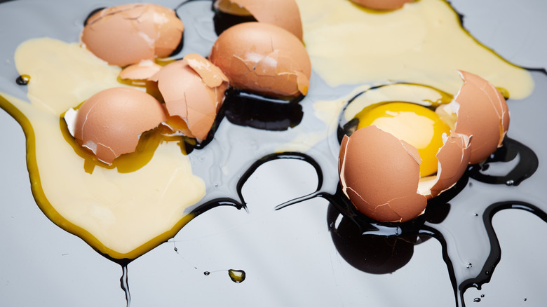 A close up of broken raw eggs on a shiny surface