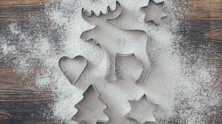 Metal cookie cutters on a wooden surface covered with flour