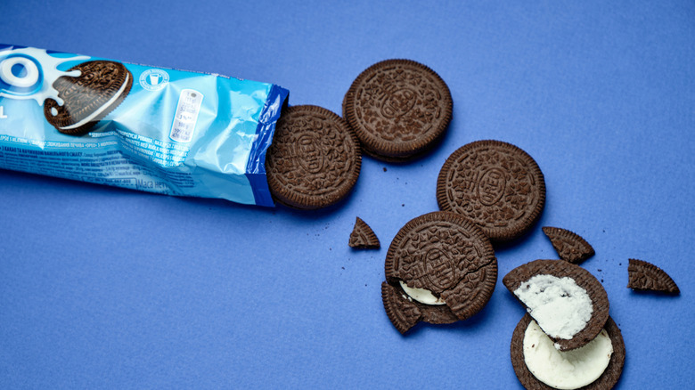 Chocolate Oreos spilling out of packaging against a blue background