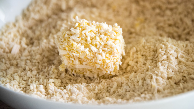 Dish of panko crumbs being used to bread a piece of food