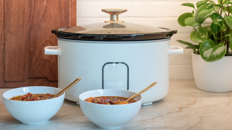 a slow cooker and two bowls of stew on a countertop