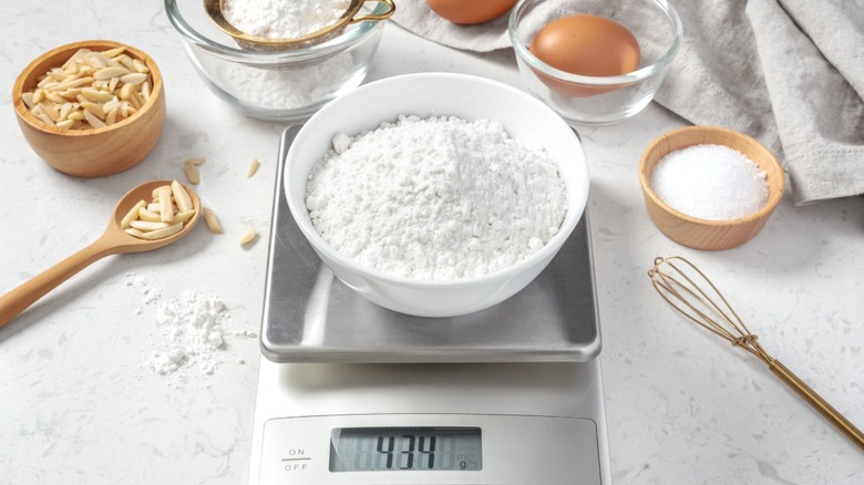 scale with flour on top in a bowl around other measured out ingredients