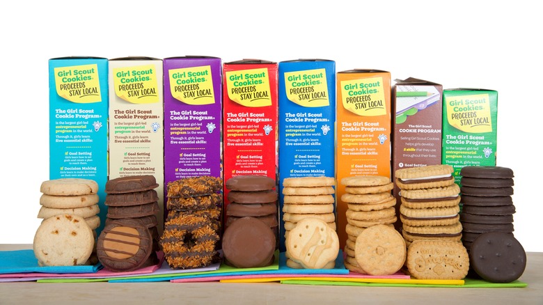 Boxes of Girl Scout cookies lined up with cookies in front