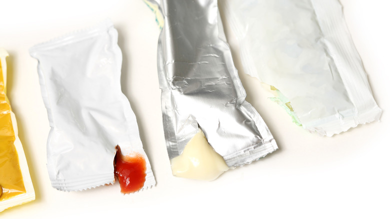 Half-open condiment packets on a white surface