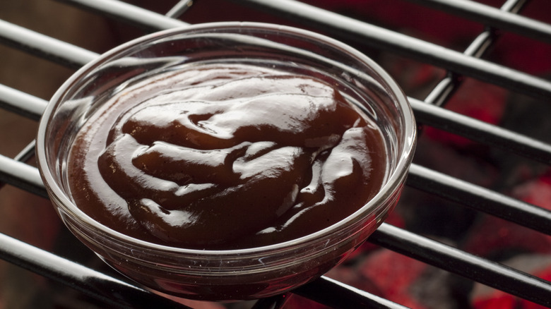 A glass bowl of BBQ sauce on the grill