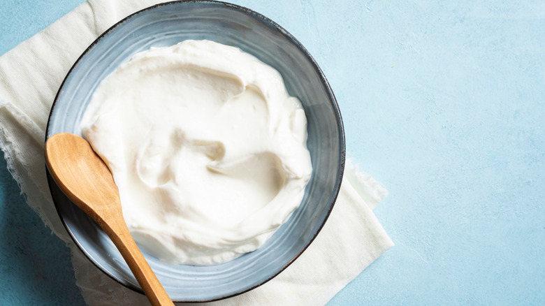 Wooden spoon in a blue bowl of Greek yogurt